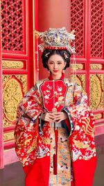 Portrait of smiling young woman standing against wall
