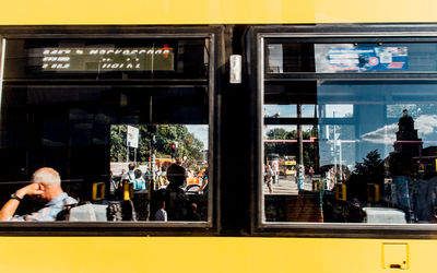 People and tram with reflection on window glass