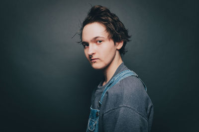 Portrait of young man standing against black background