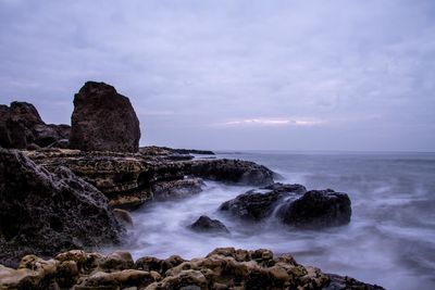 Scenic view of rocks on shore against sky