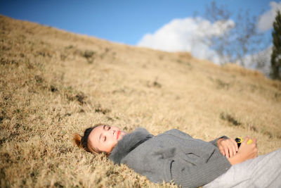 Midsection of man lying down on land against sky