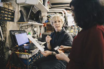 Female mechanic showing receipt to customer holding credit card at auto repair shop