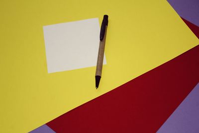 High angle view of pen on table against yellow background