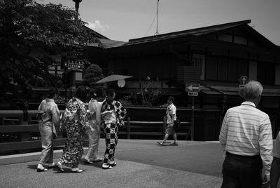 Rear view of people standing on street against buildings