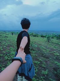 Rear view of people on sea shore against sky
