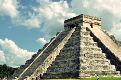 Low angle view of chichen itza against cloudy sky