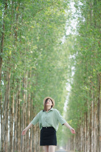 Portrait of young woman standing against trees