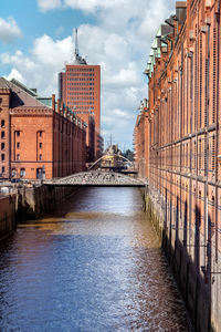 Bridge over river amidst buildings in city against sky