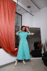 Woman standing near curtain at home