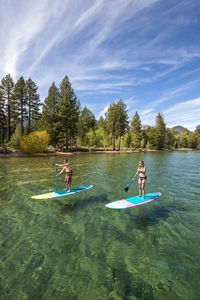 A man and woman stand up paddle boarding on lake tahoe, ca