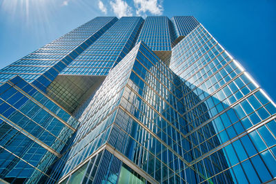 Low angle view of modern glass building against blue sky