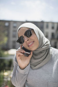 Muslim woman wearing a hijab and sunglasses taking a phone call