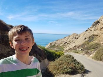 Portrait of smiling boy in sea against sky