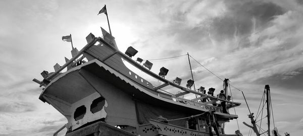 Low angle view of traditional windmill against cloudy sky