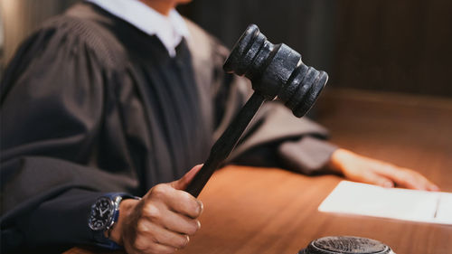 Midsection of man holding umbrella on table