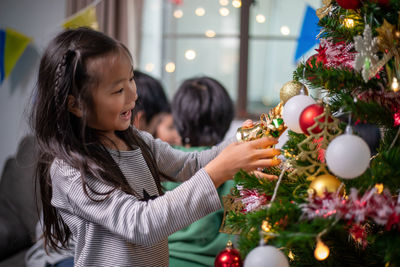 Side view of woman decorating christmas tree