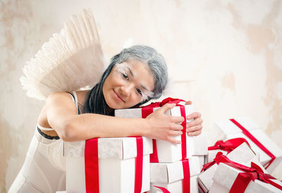 Portrait of female model in angel costume holding christmas presents