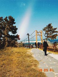 Rear view of man walking on footpath against sky