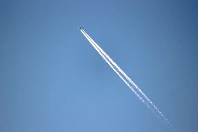 Low angle view of vapor trail against blue sky