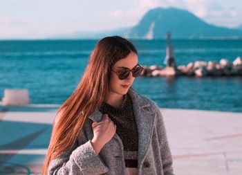 Woman wearing sunglasses while standing against sea