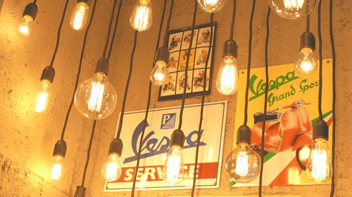 Low angle view of illuminated light bulbs hanging at night