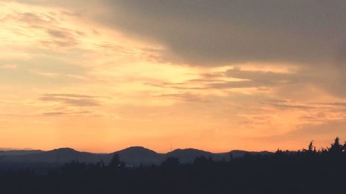 Scenic view of silhouette mountains against dramatic sky