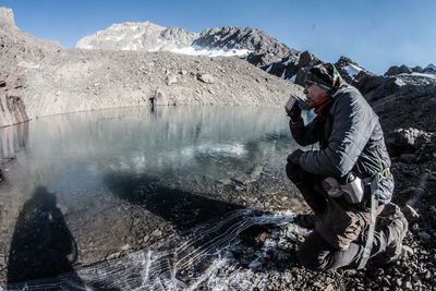 Man having drink at lakeshore during winter