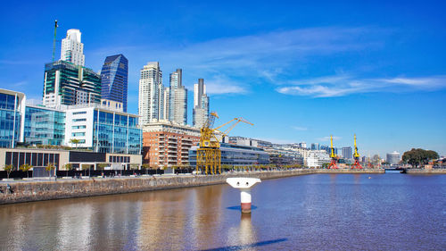 River by modern buildings against sky in city