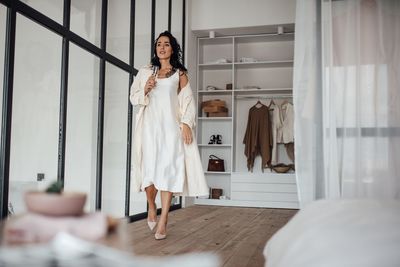 Woman in white dress against wardrobe at home