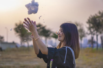 Portrait of young woman holding umbrella against sky