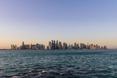 Sea and cityscape against clear sky