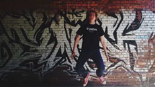 Man jumping in front of graffiti wall