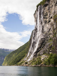 Scenic view of waterfall and mountains against sky