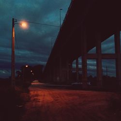 Illuminated street light against cloudy sky