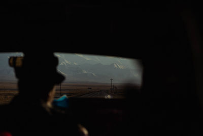 Silhouette woman looking through window