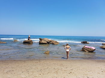 People on beach against clear sky