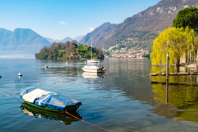 Comacina island, photographed in autumn, with trees, boats and piers around.