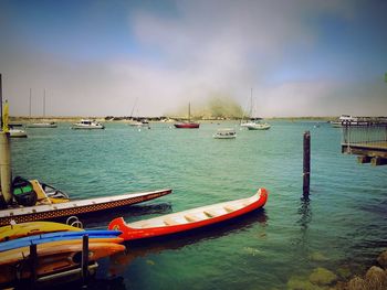 Boats moored at harbor against sky