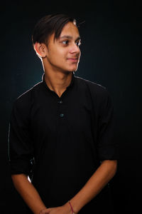 Young man looking away against black background