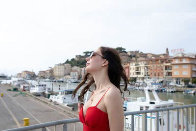 Side view of woman standing on footbridge at harbor