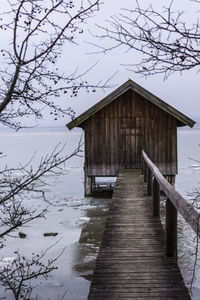 Built structure by lake against sky during winter