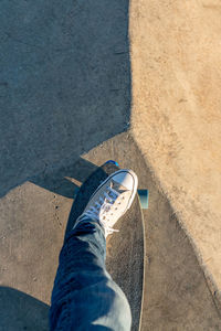 High-angle view of one foot on a skateboard in skatepark at golden hour