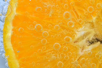 Slice of orange fruit in sparkling water. orange fruit slice covered by bubbles in carbonated water