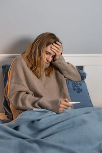 Sick woman checking temperature at home