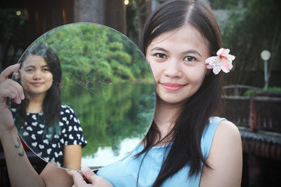 Portrait of woman with sister reflecting in mirror