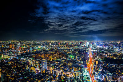 High angle view of illuminated city buildings against sky at night