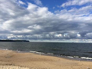 Scenic view of beach against cloudy sky