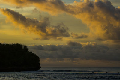 Scenic view of sea against dramatic sky during sunset
