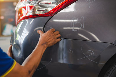 Cropped image of mechanic examining car in workshop