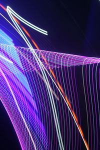 Low angle view of light trails over blue background